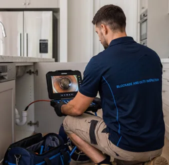 Plumber clearing a blocked toilet in a Five Dock bathroom